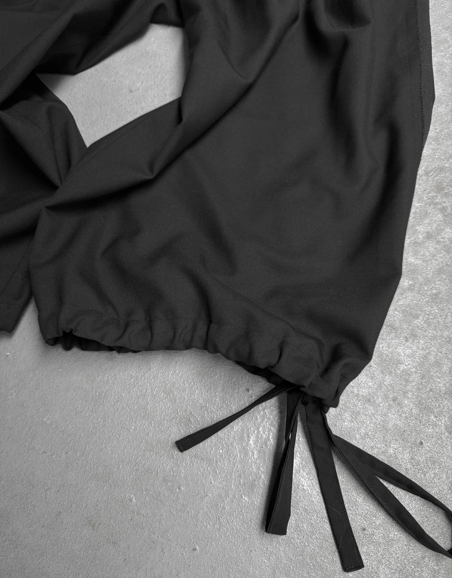 Black pants with drawstring on a gray surface