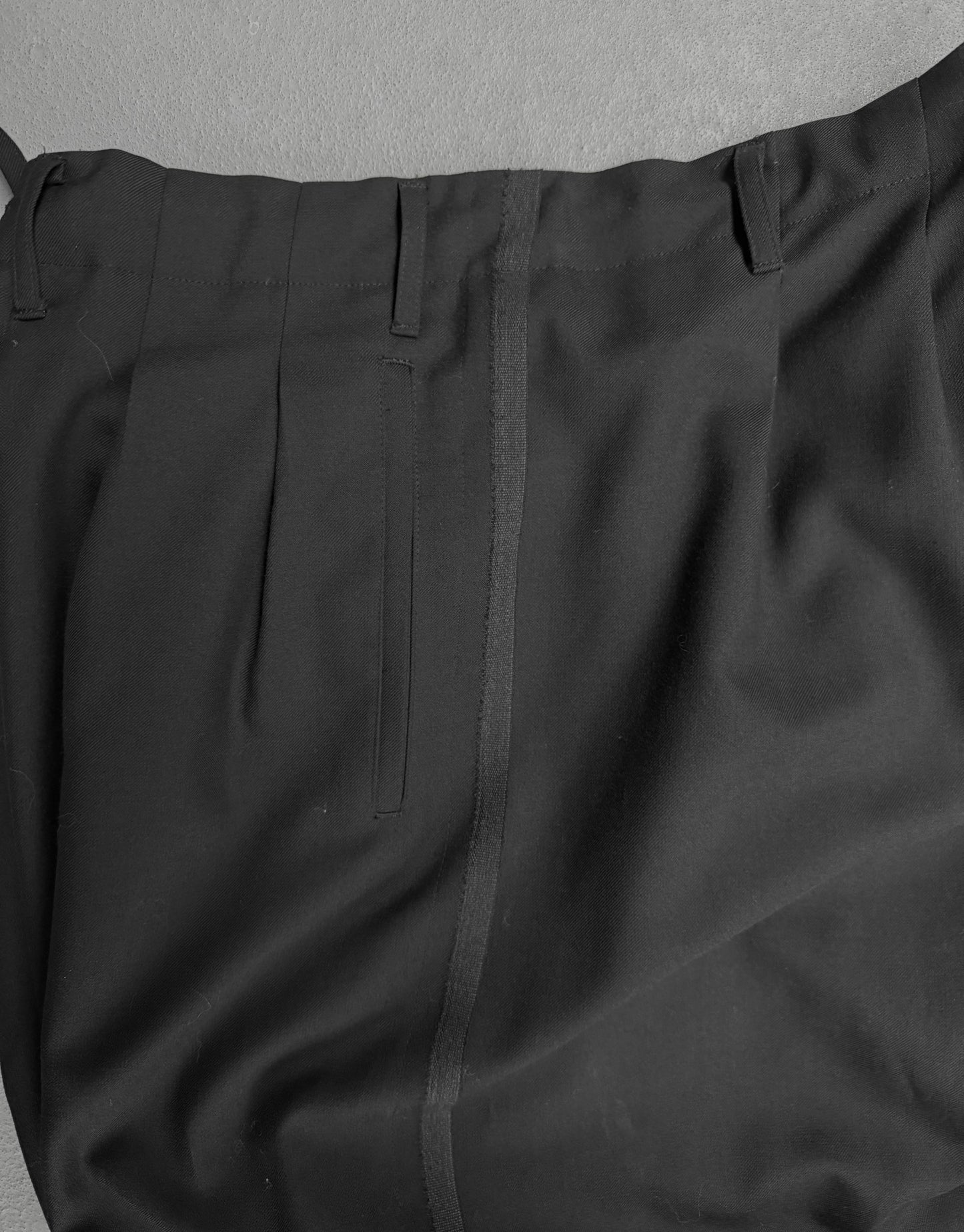 Close-up of black pants with a gray background