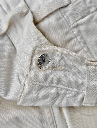 Close-up of a white denim jacket with a button and stitching detail.