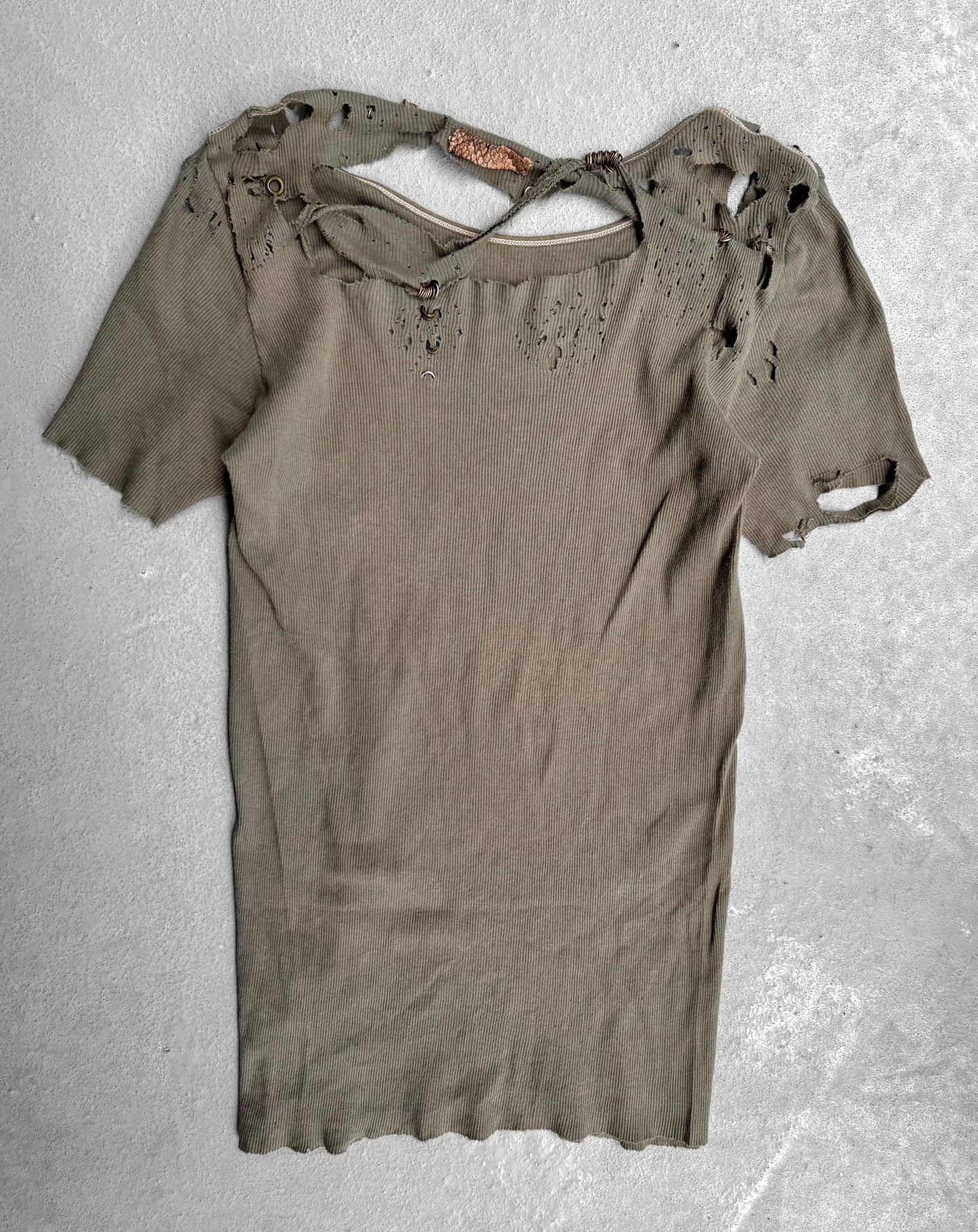 Ripped green t-shirt on a textured gray background