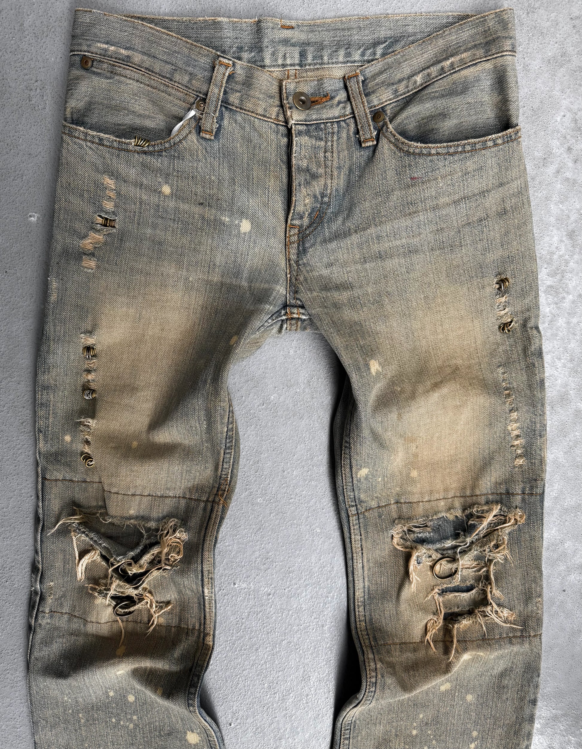 Ripped and worn denim jeans on a gray background