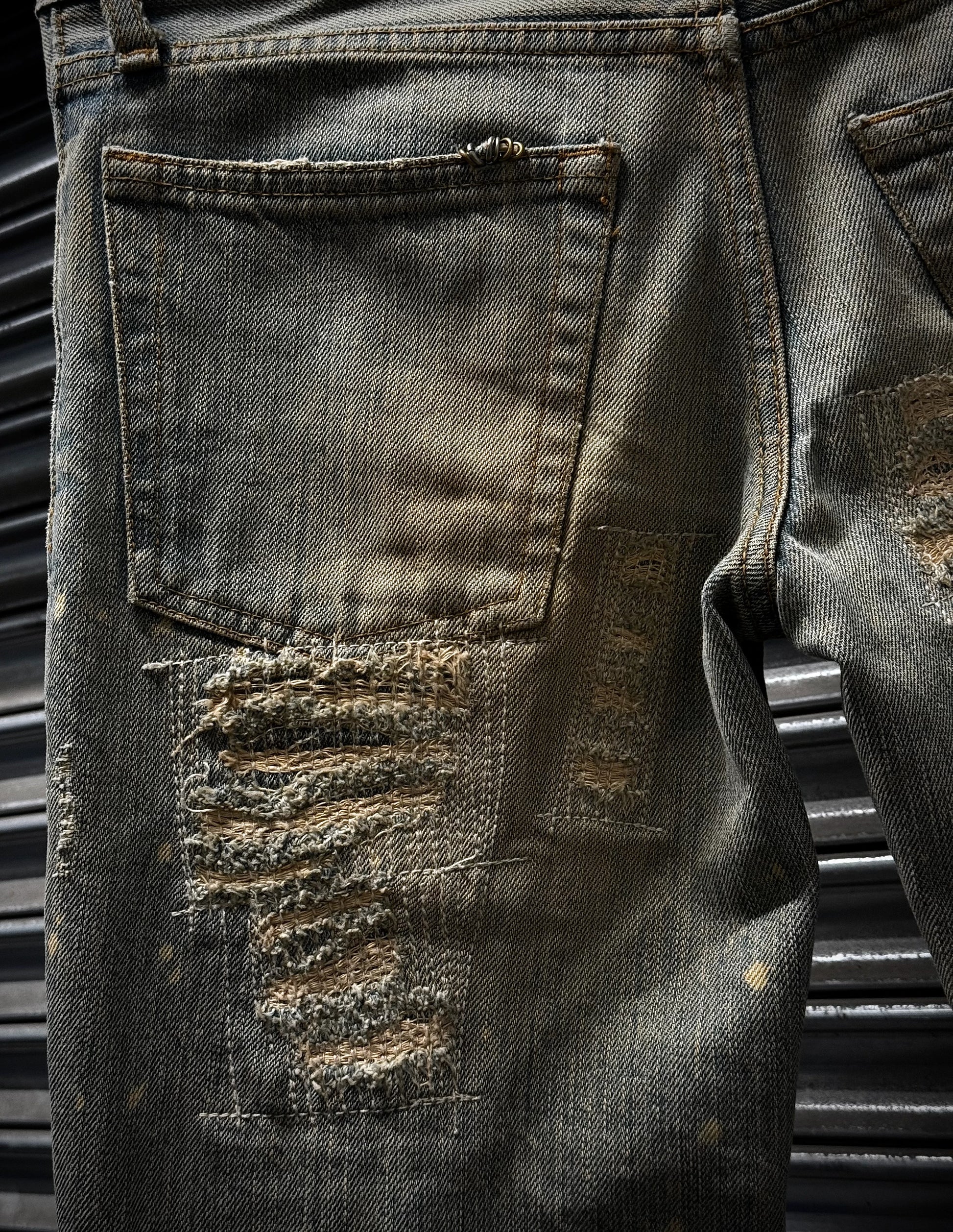 Close-up of a distressed black denim jacket with metal buttons on a dark background