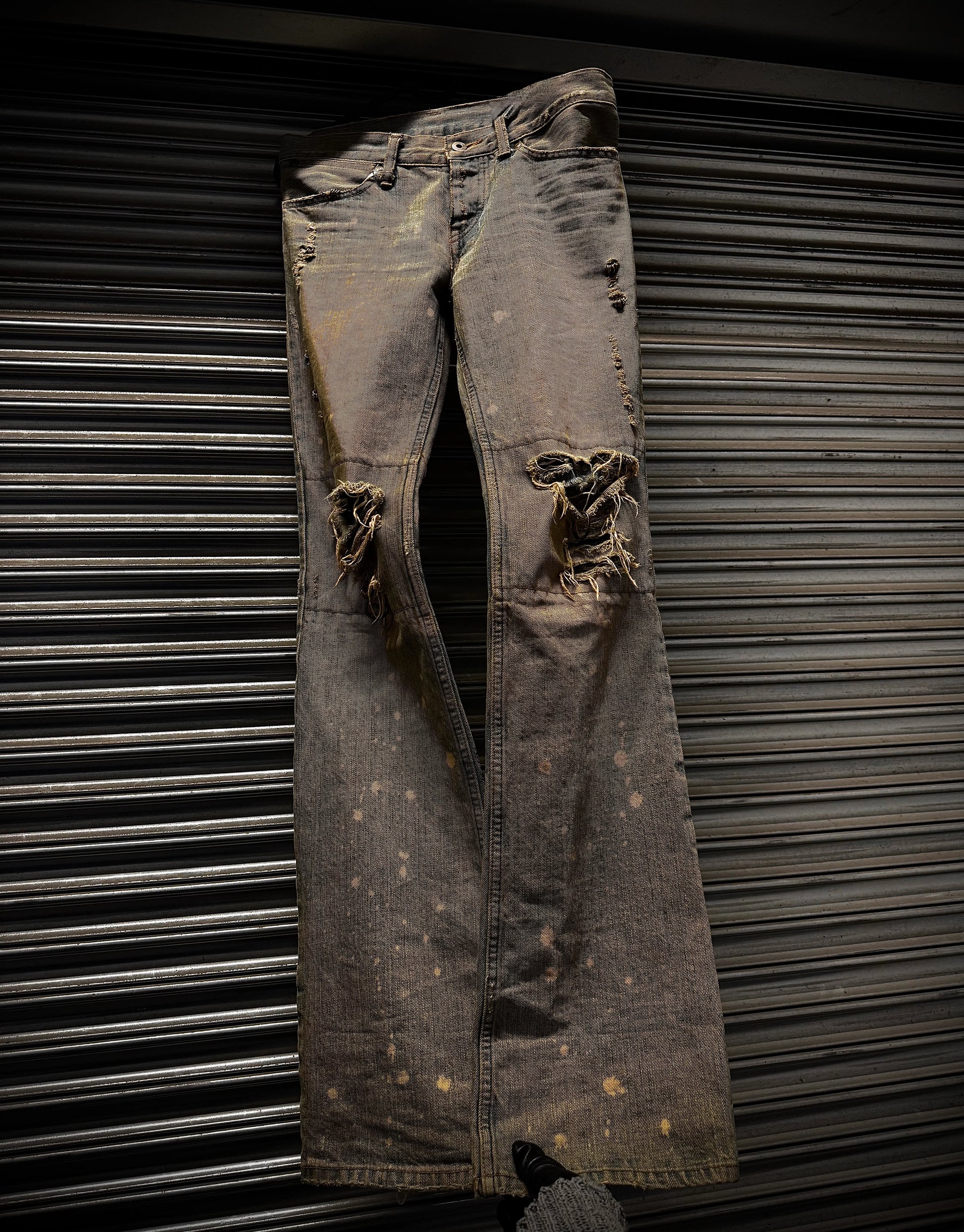 Distressed black jeans against a metallic background