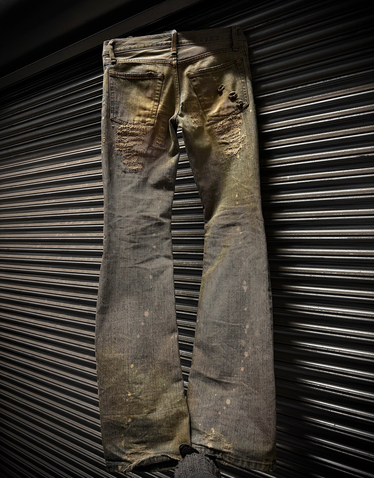 Worn denim jeans against a metallic background