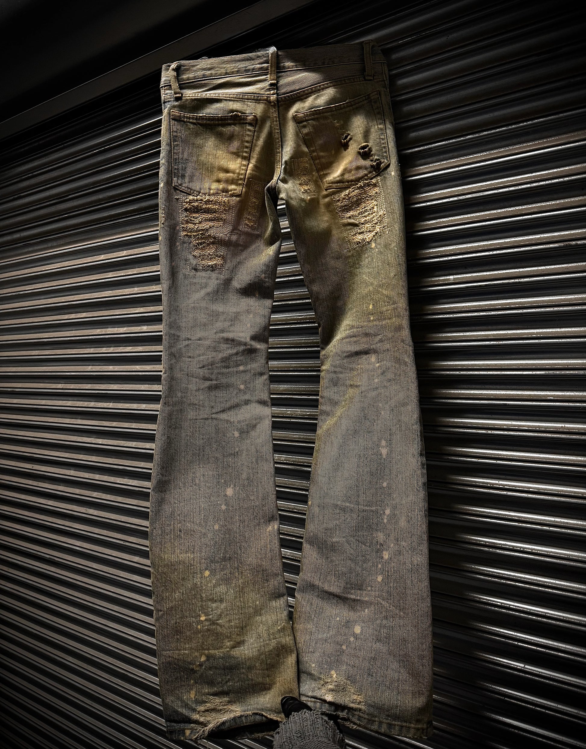 Worn denim jeans against a metallic background