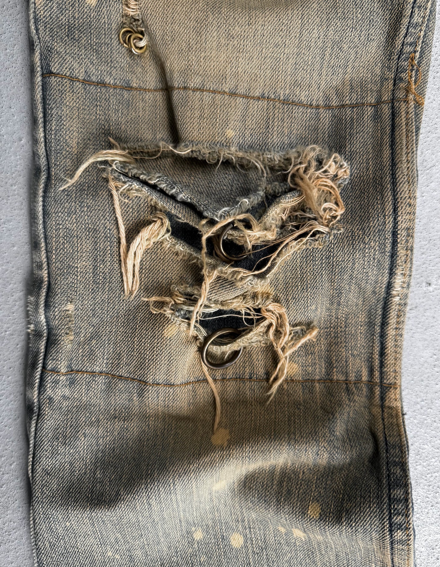 Ripped pocket of a worn denim jacket on a gray background
