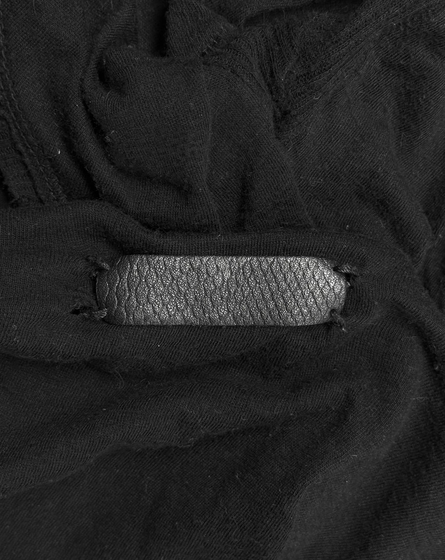 Close-up of a black leather strap on a textured black fabric background