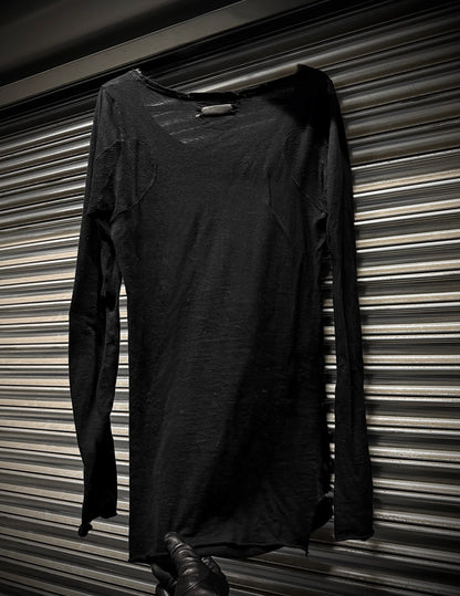 Black long-sleeve dress hanging against a striped wall.