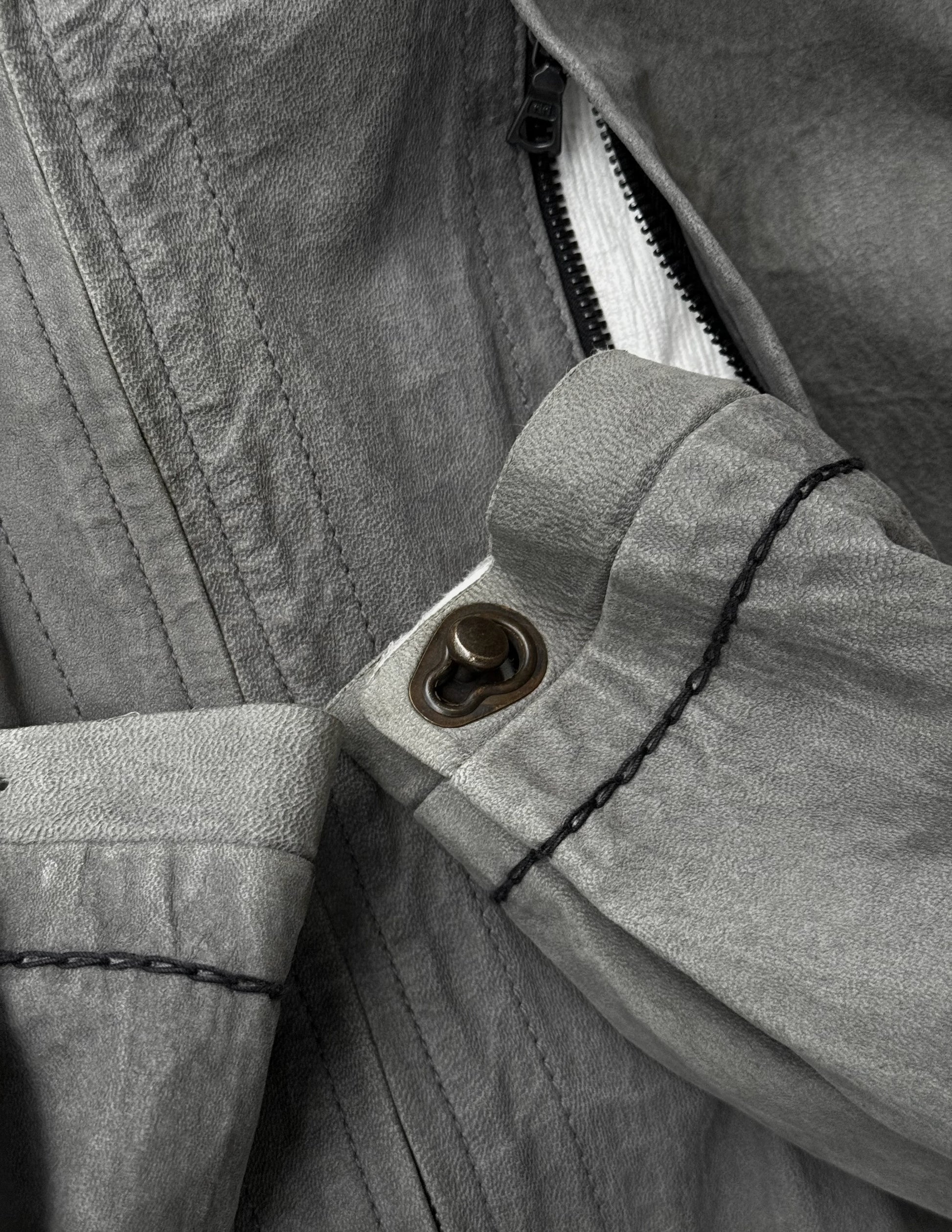 Close-up of a button on a jacket with a zipper partially open.