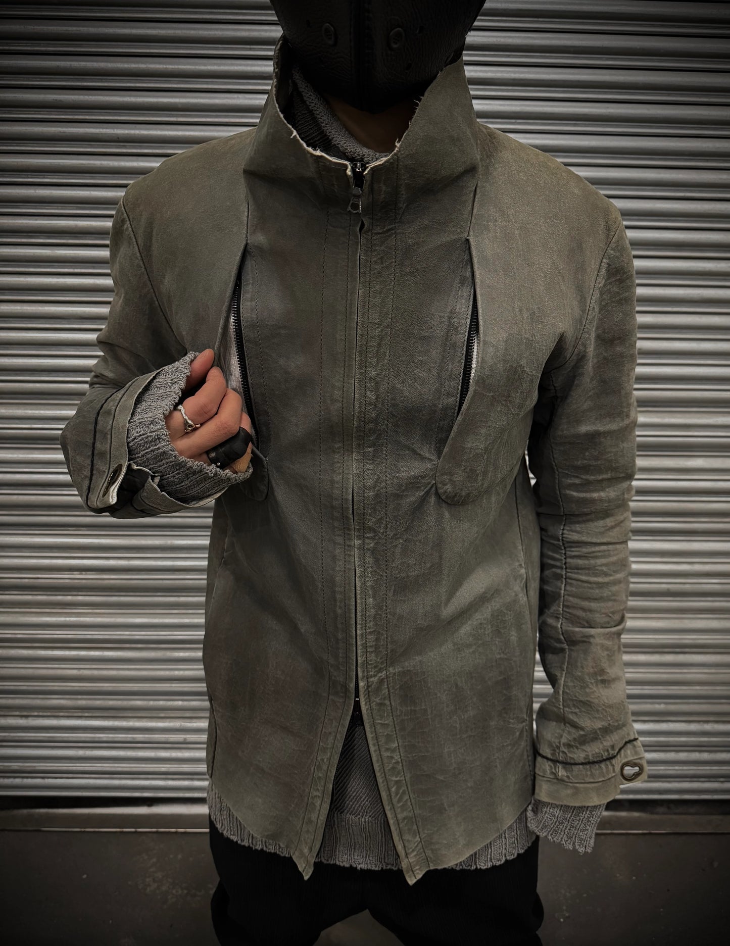 Person wearing a green trench coat against a metallic background