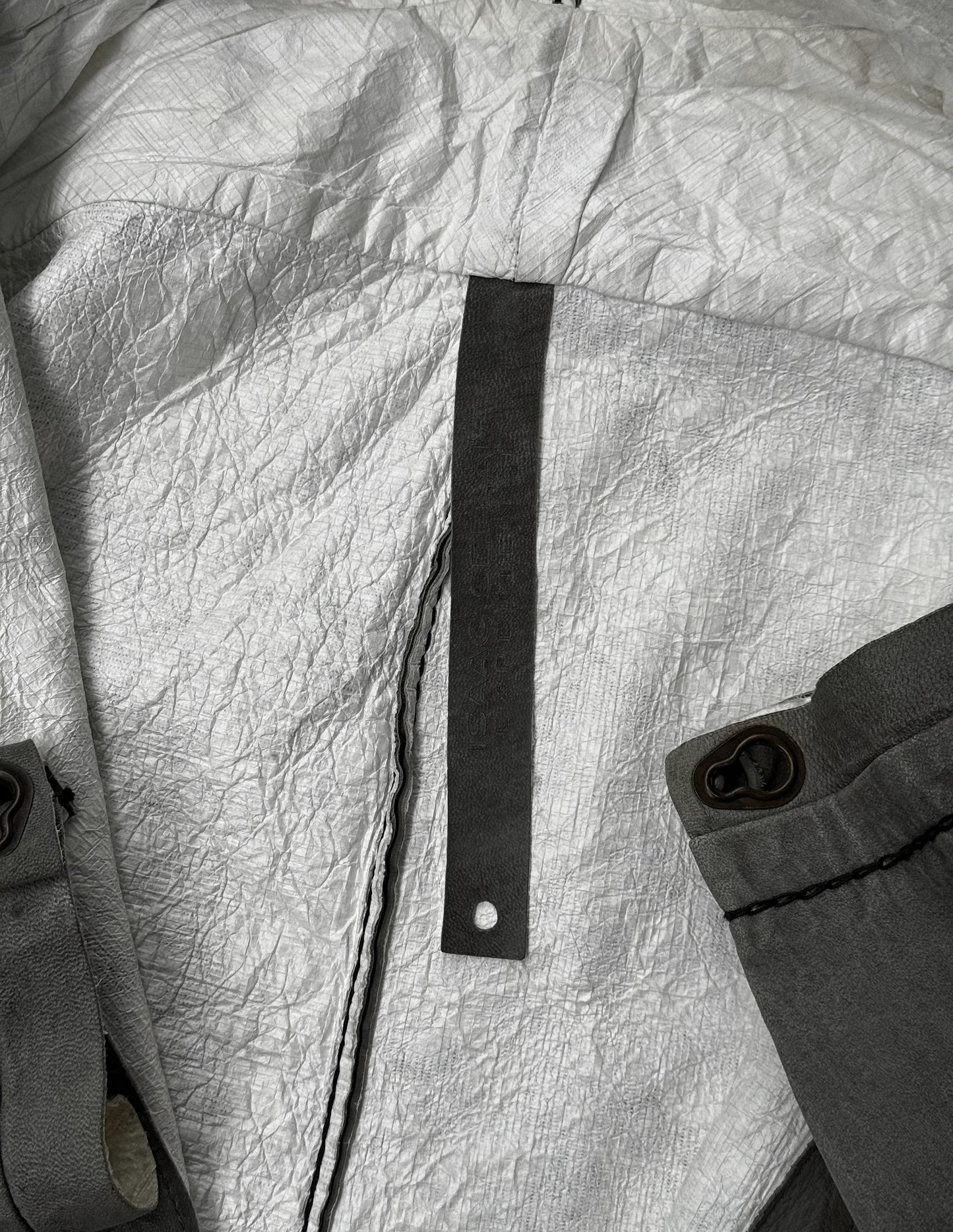 Close-up of a textured fabric surface with a black strap and button.