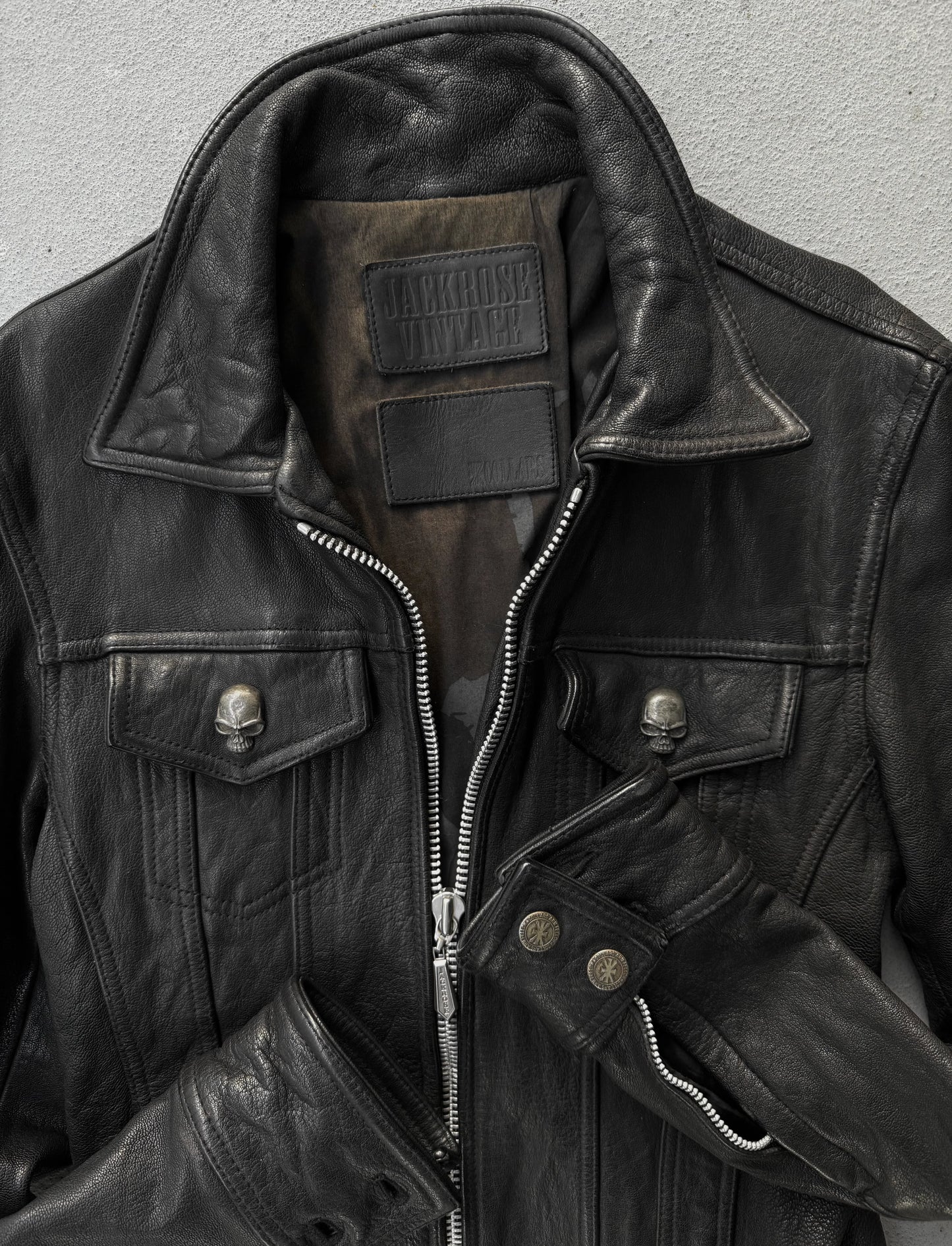 Close-up of a black leather jacket with visible branding on a gray background