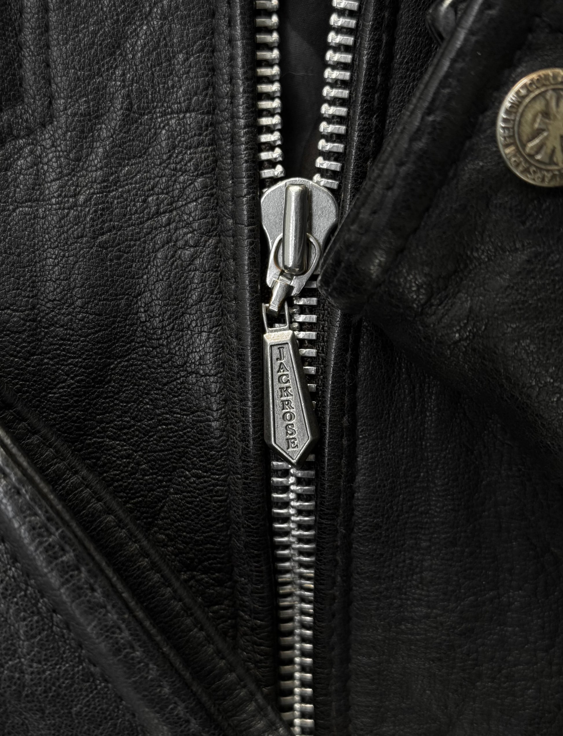 Close-up of a zipper on a black leather jacket with a brand logo.