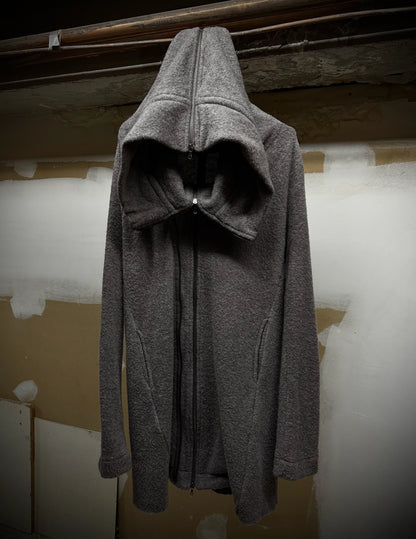 Gray hooded coat hanging against a plain wall.