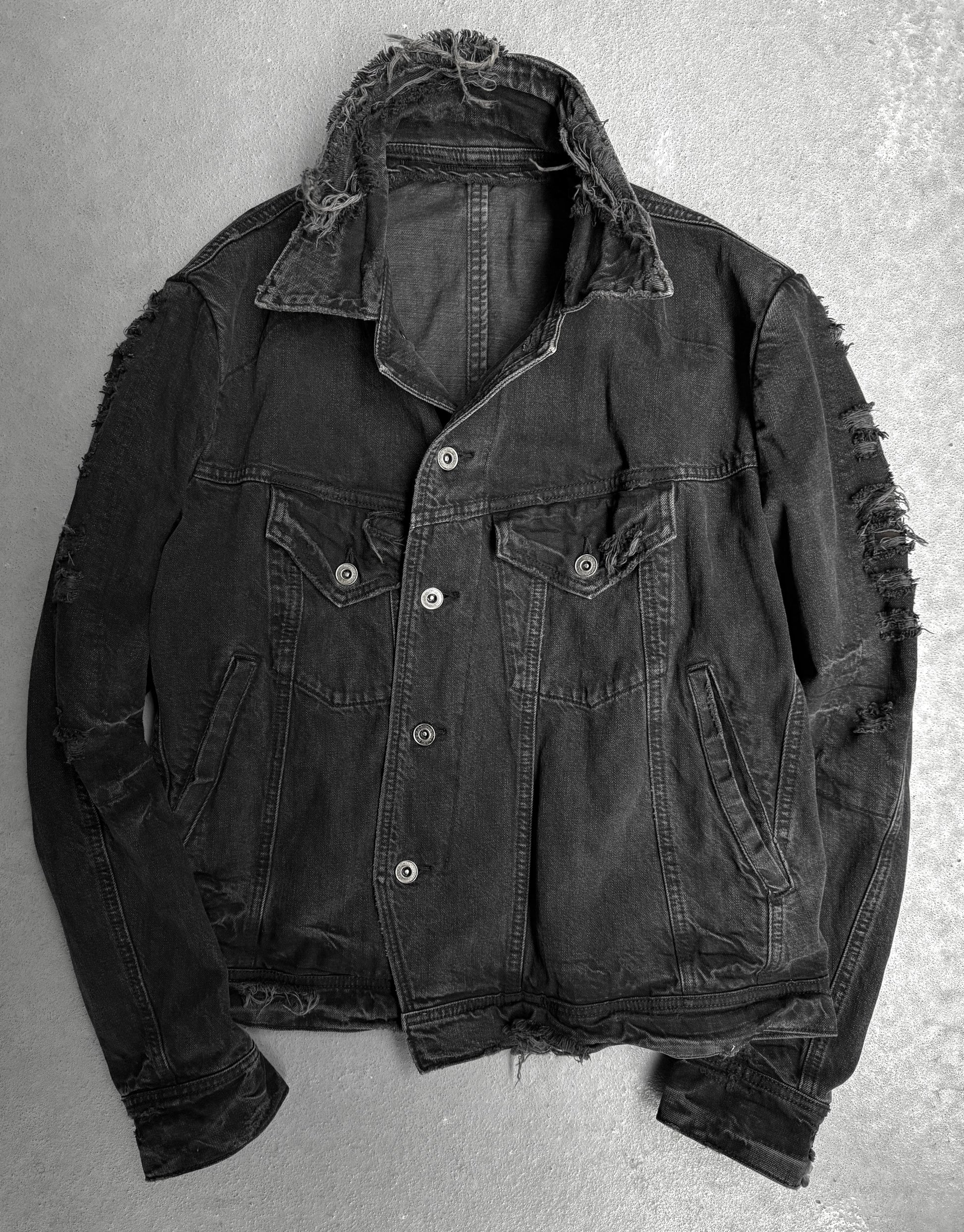 Ripped black denim jacket on a gray background
