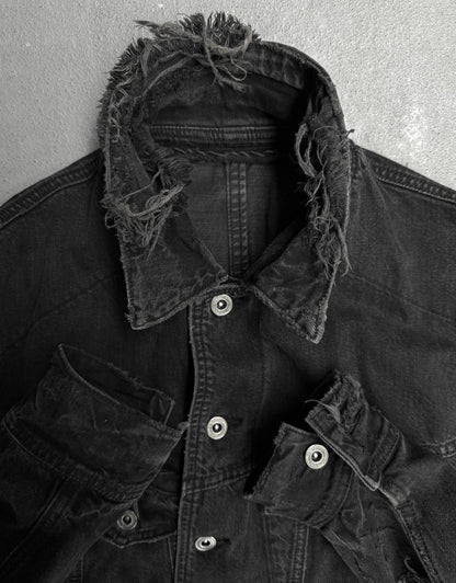 Black denim jacket with frayed collar against a gray background