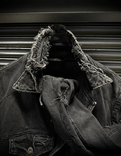 Person wearing a dark denim jacket with lace trim against a metallic background