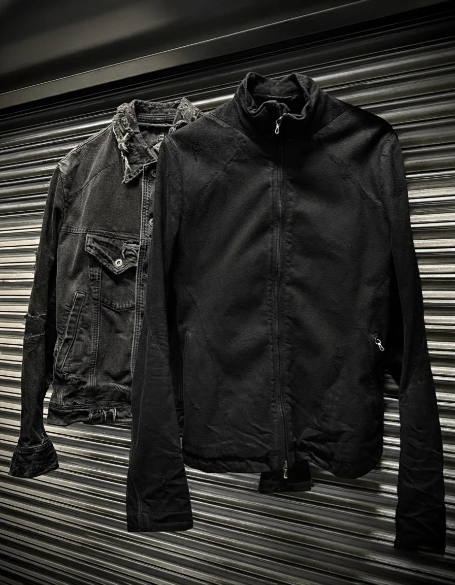 Two jackets, one dark denim and one black, against a corrugated metal background.