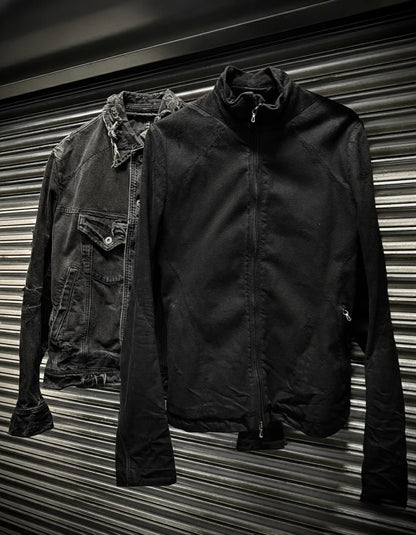 Two jackets, one dark denim and one black, against a corrugated metal background.