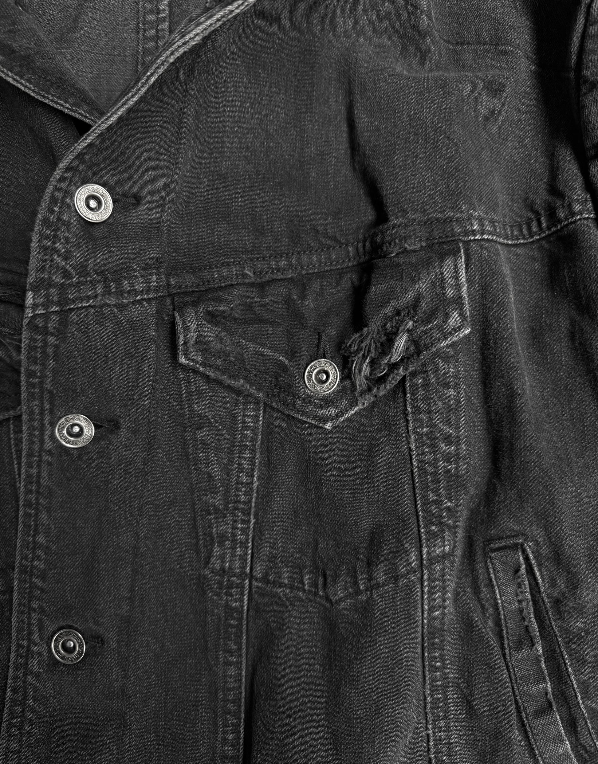 Close-up of a dark denim jacket with buttons and a pocket.