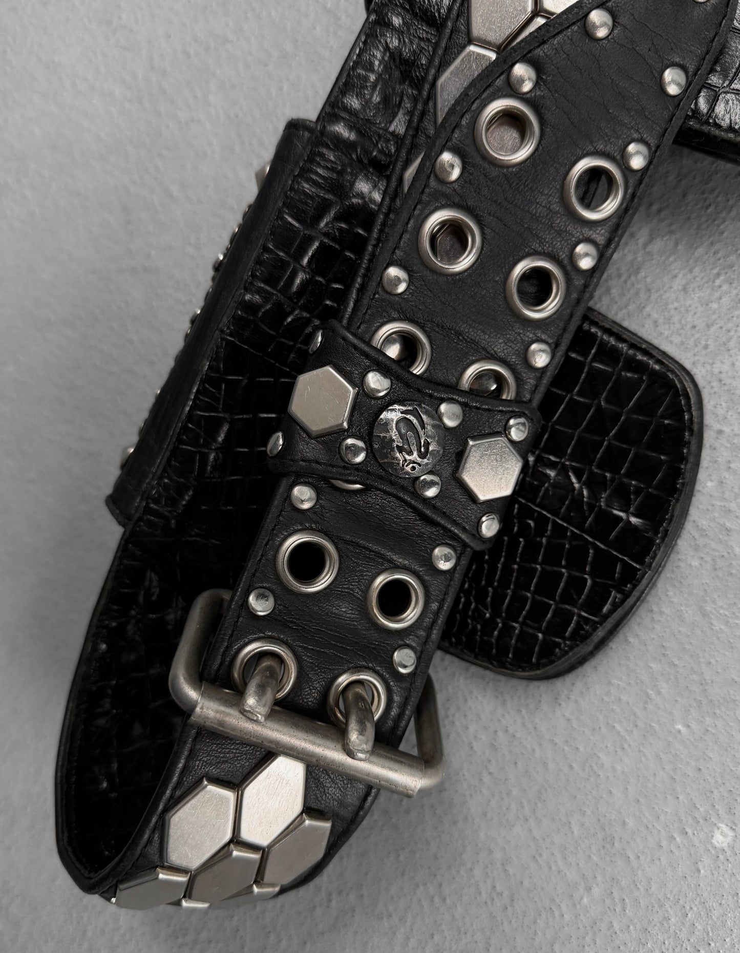 Black leather belt with silver studs and buckles on a gray background