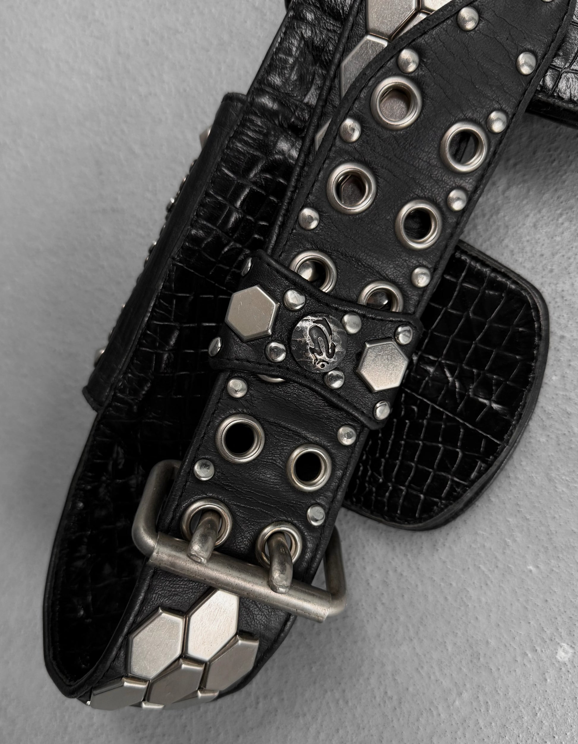 Black leather belt with silver studs and buckles on a gray background