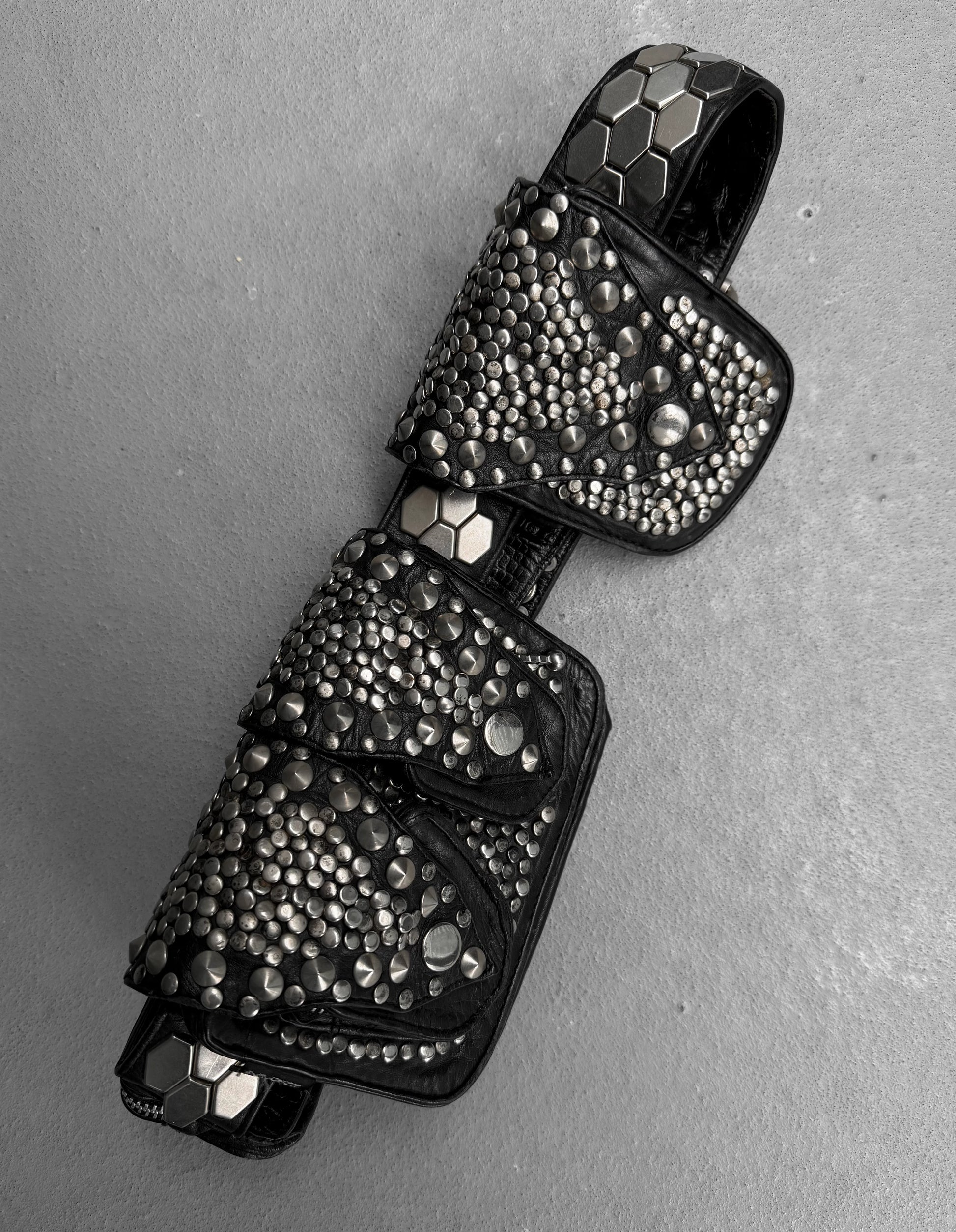 Black studded key-shaped pendant on a gray background