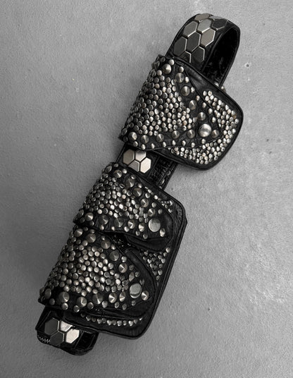 Black studded key-shaped pendant on a gray background