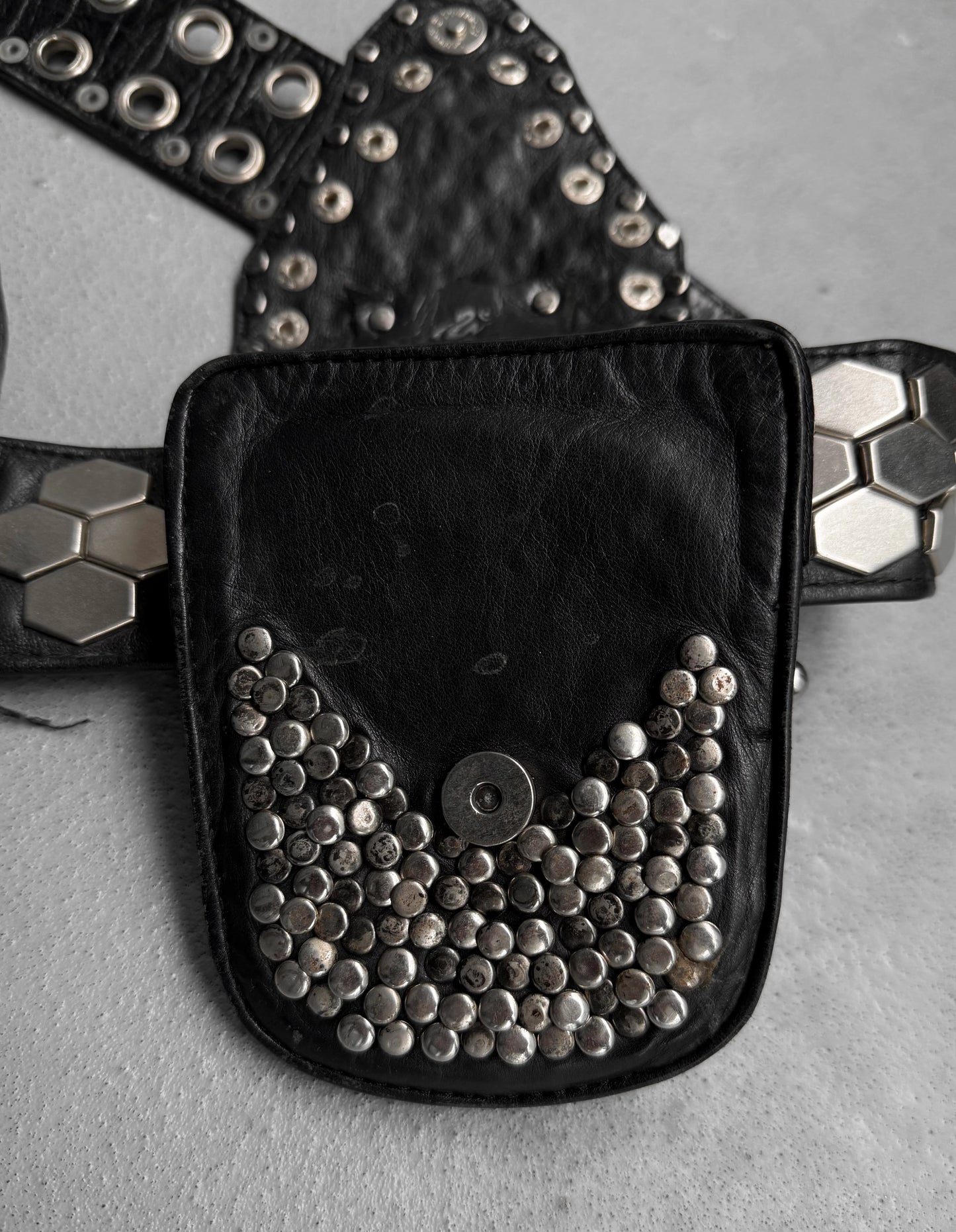 Black belt bag with silver studs on a gray surface