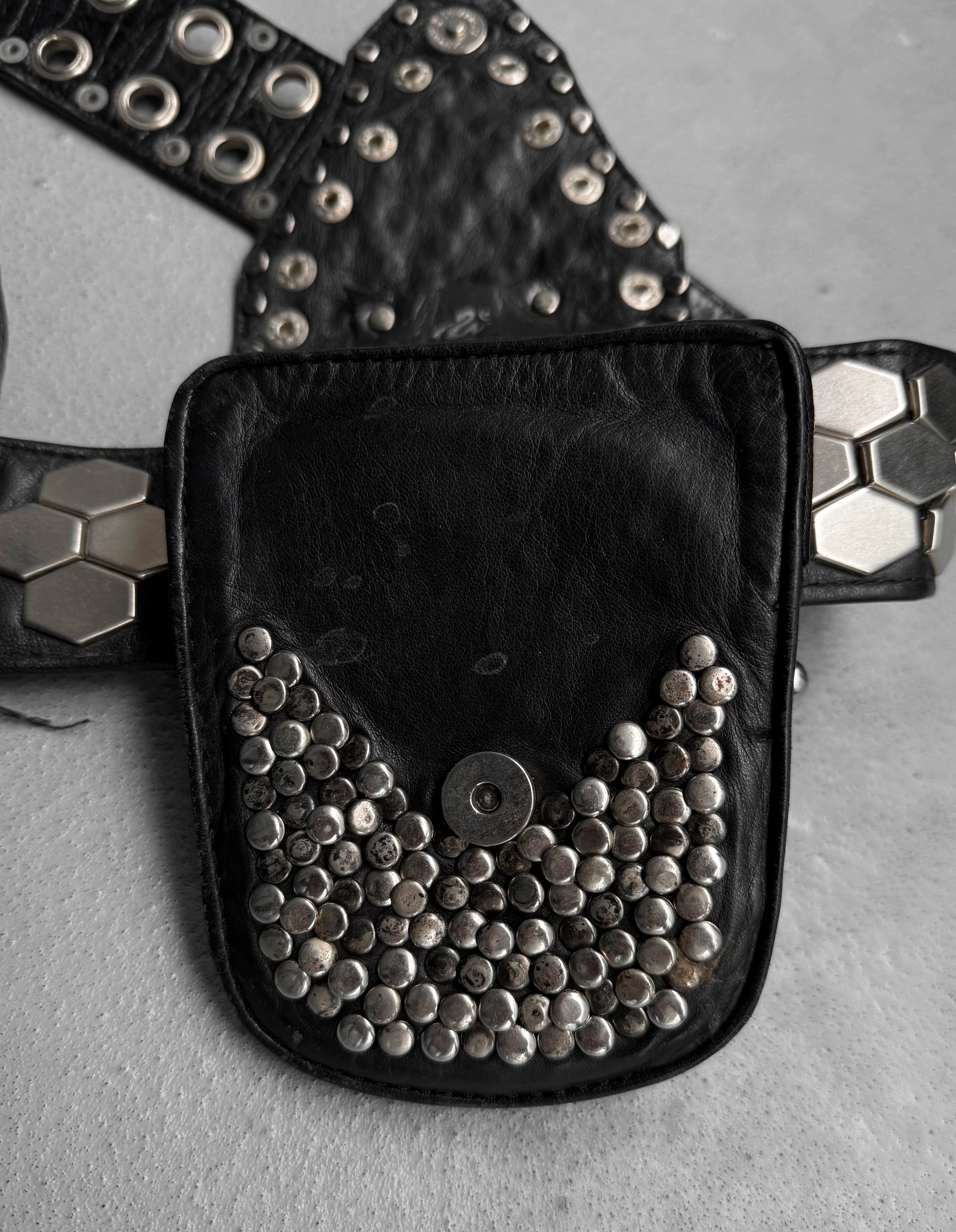 Black belt bag with silver studs on a gray surface