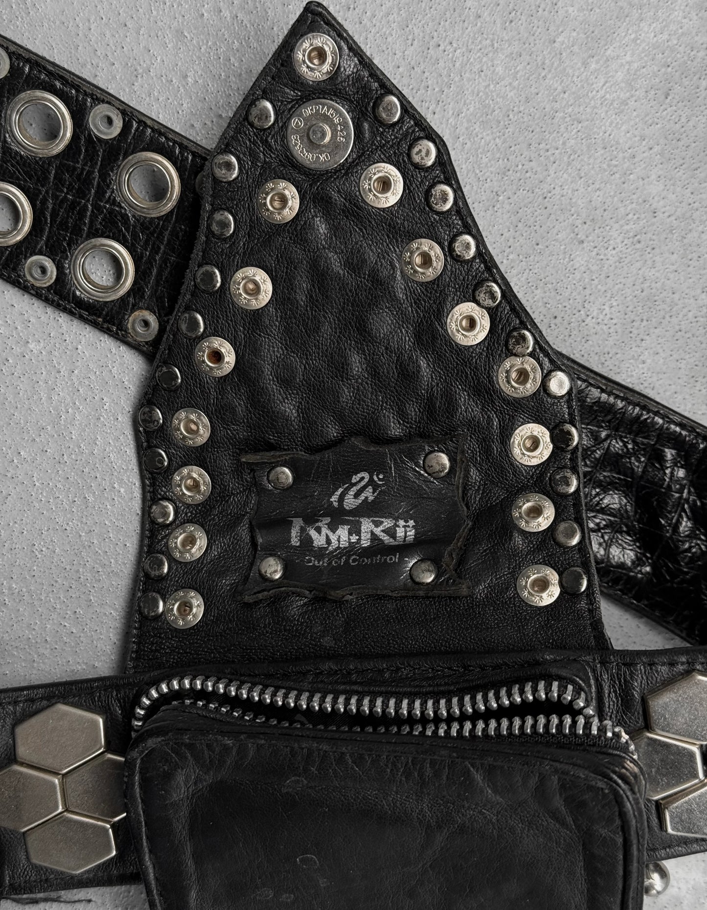 Black leather vest with studs and a brand label on a gray background