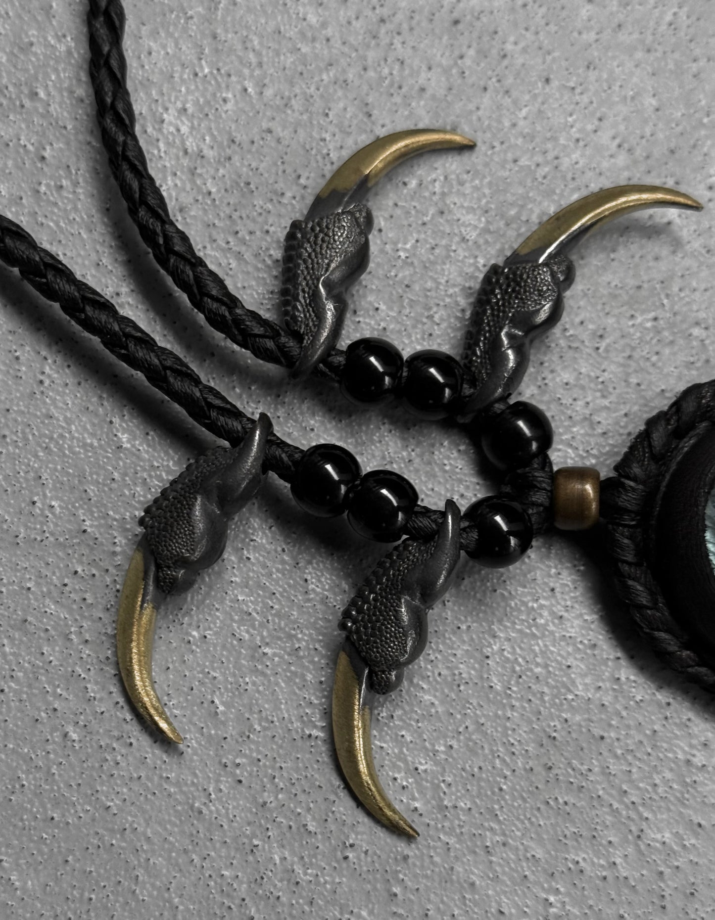 Necklace with claw-like pendants and black beads on a gray background