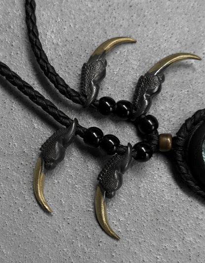 Necklace with claw-like pendants and black beads on a gray background