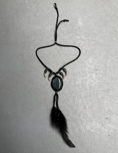 Black necklace with feather and stone pendant on a gray background