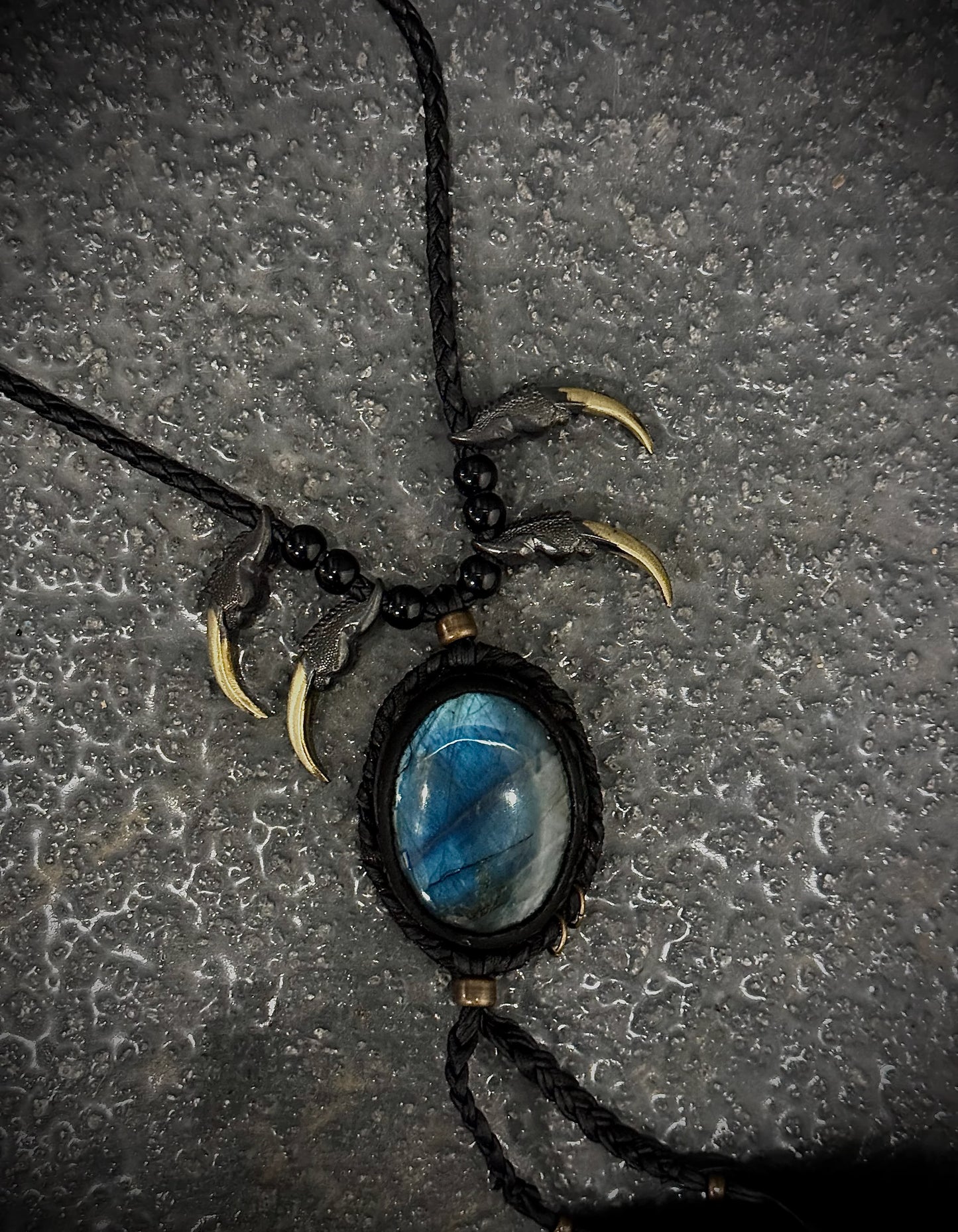 Necklace with blue stone pendant and bear claws on a textured surface