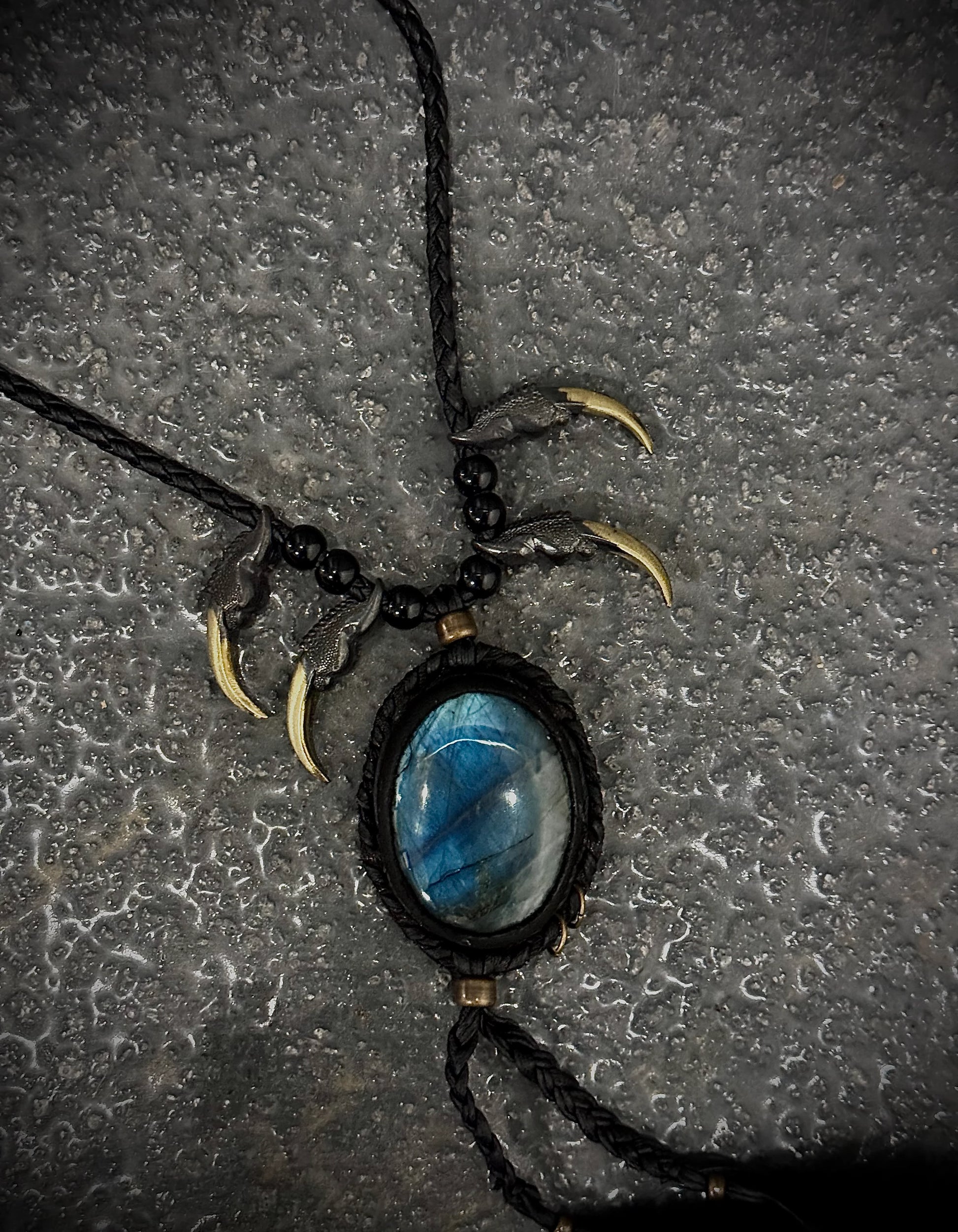 Necklace with blue stone pendant and bear claws on a textured surface