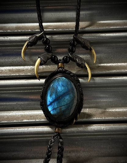 Necklace with blue stone and claw-like elements on a corrugated metal background