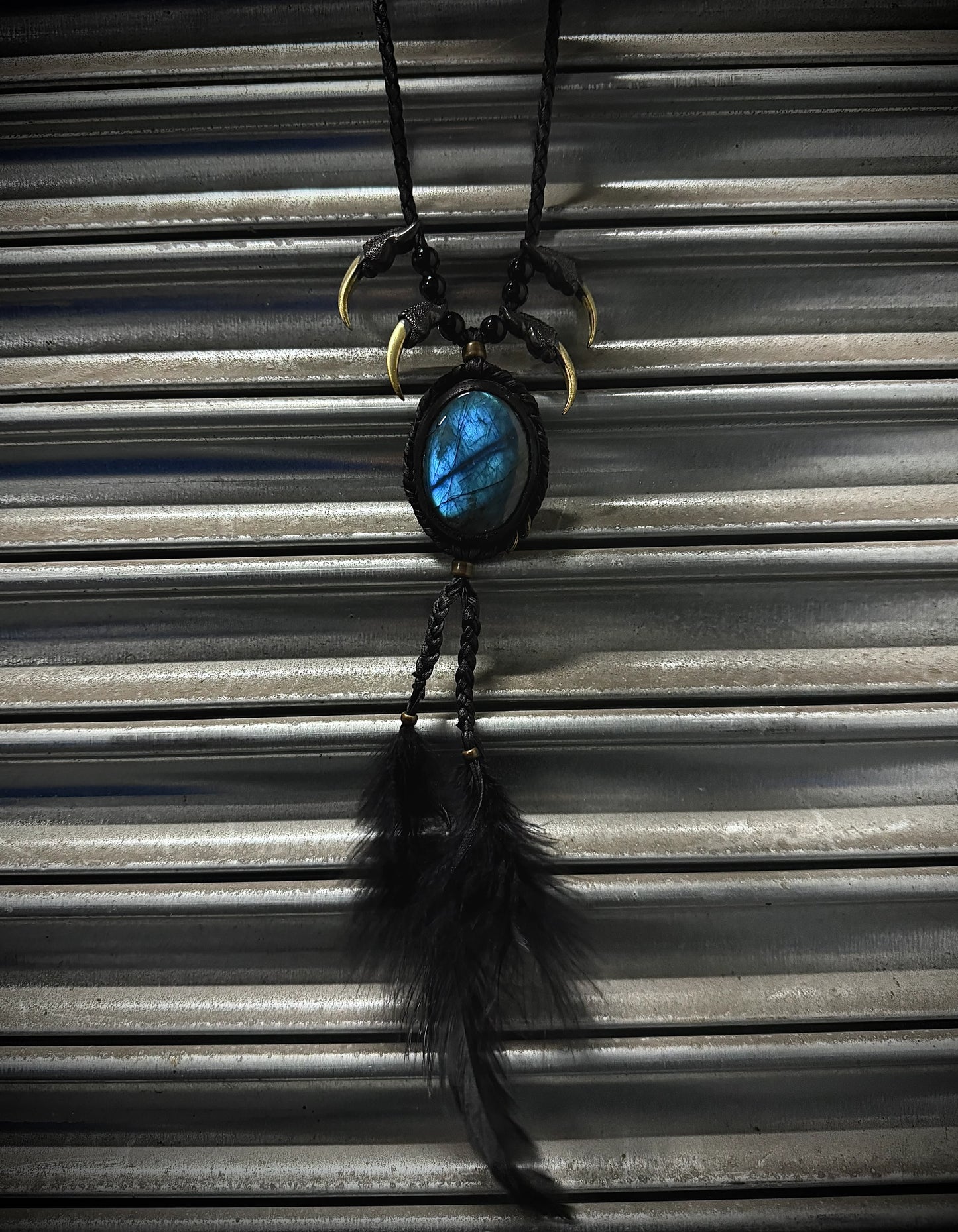 Necklace with a blue stone and feather pendant on a corrugated metal background