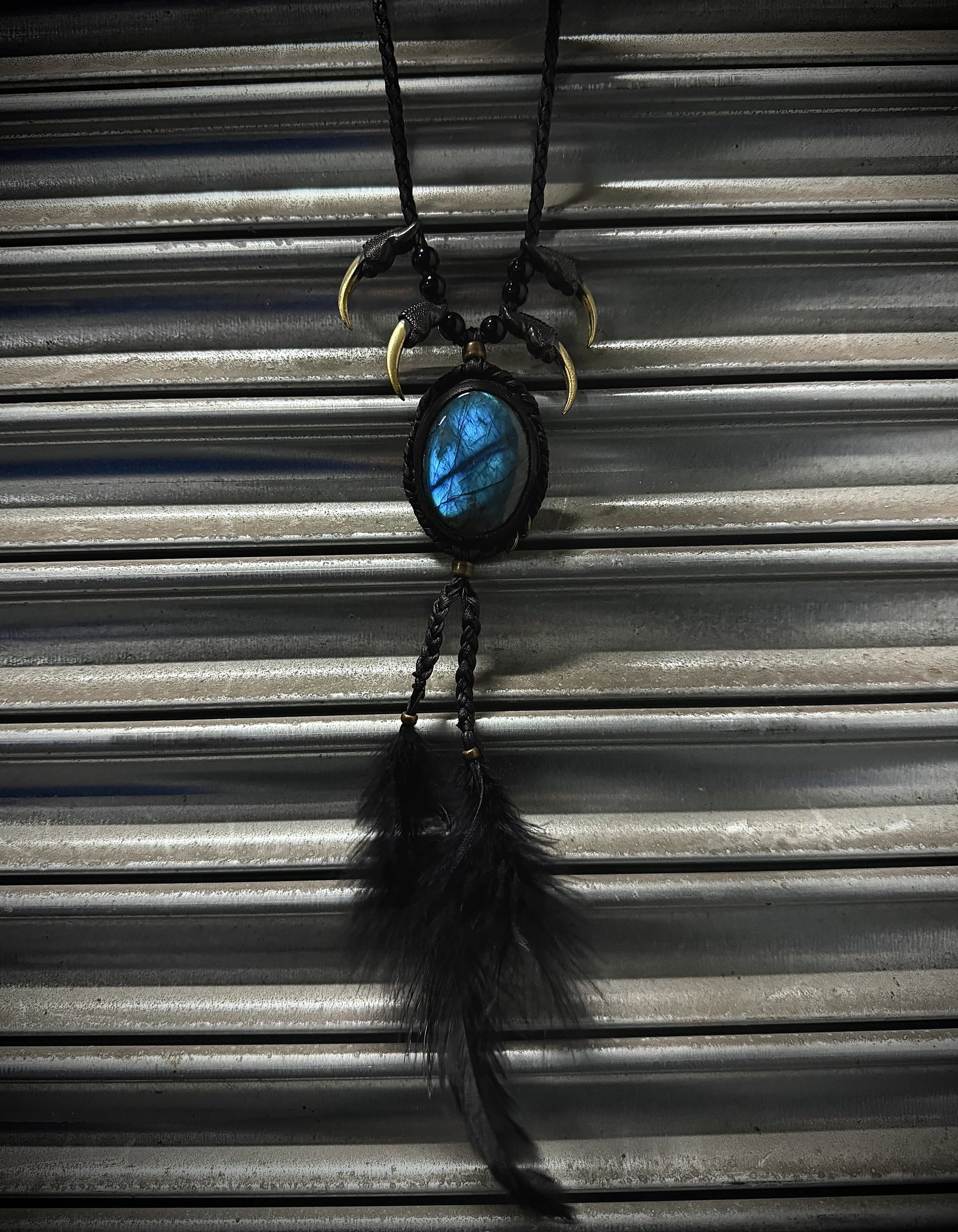 Necklace with a blue stone and feather pendant on a corrugated metal background