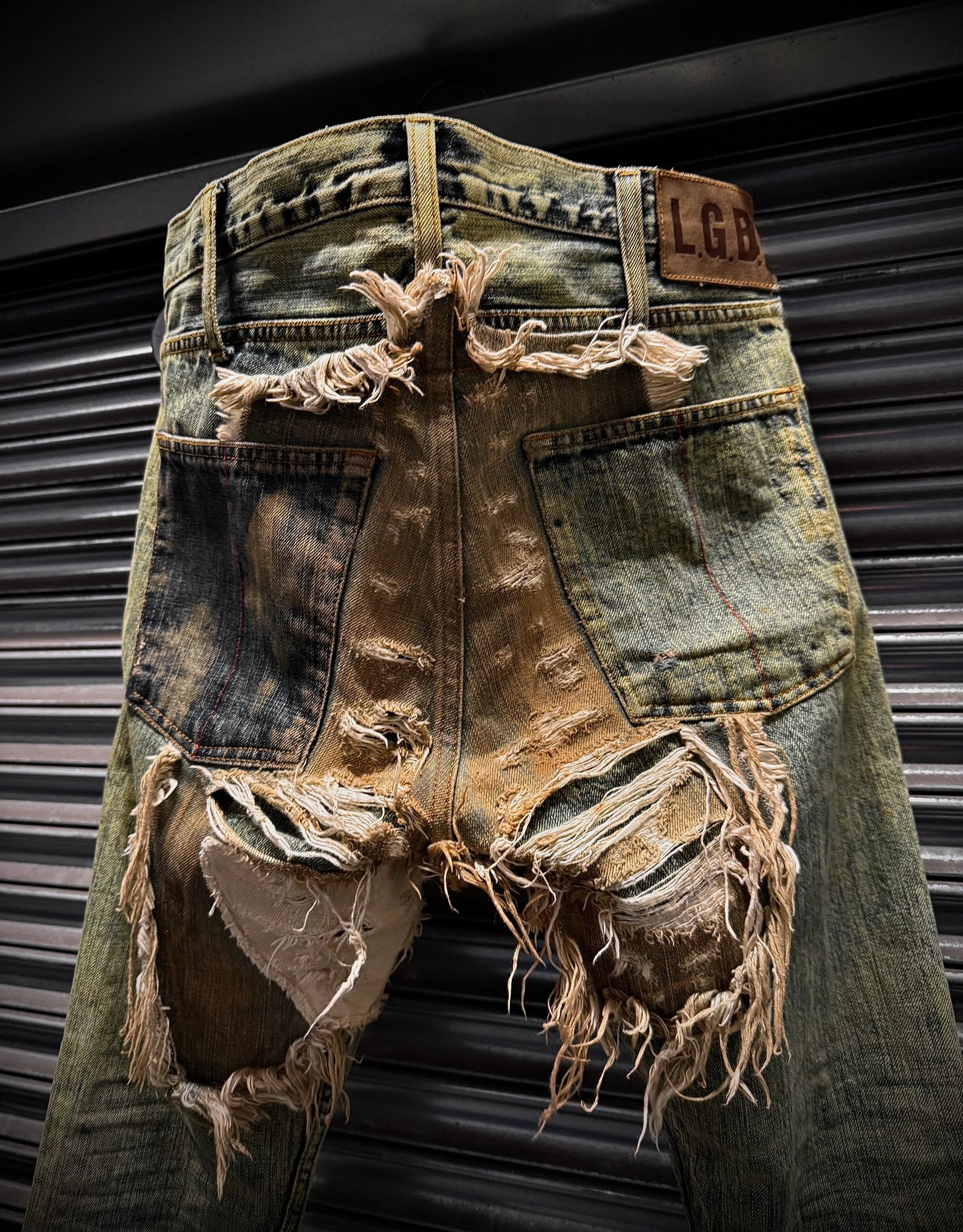 Distressed denim shorts with frayed edges against a metallic background