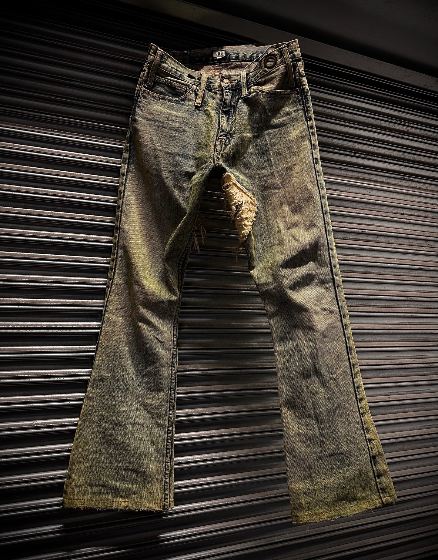 Distressed green jeans on a metallic surface