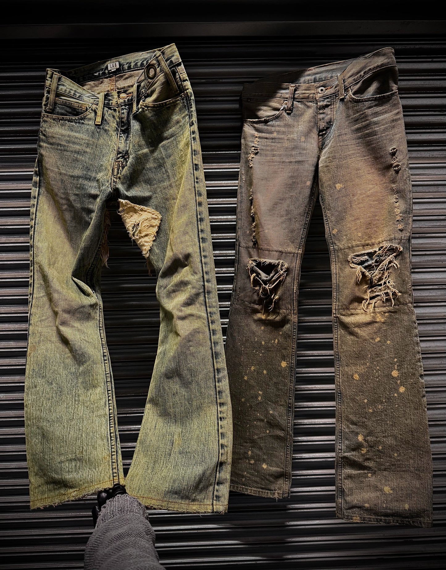Two pairs of distressed jeans on a metallic surface