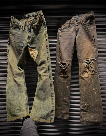 Two pairs of distressed jeans on a metallic surface