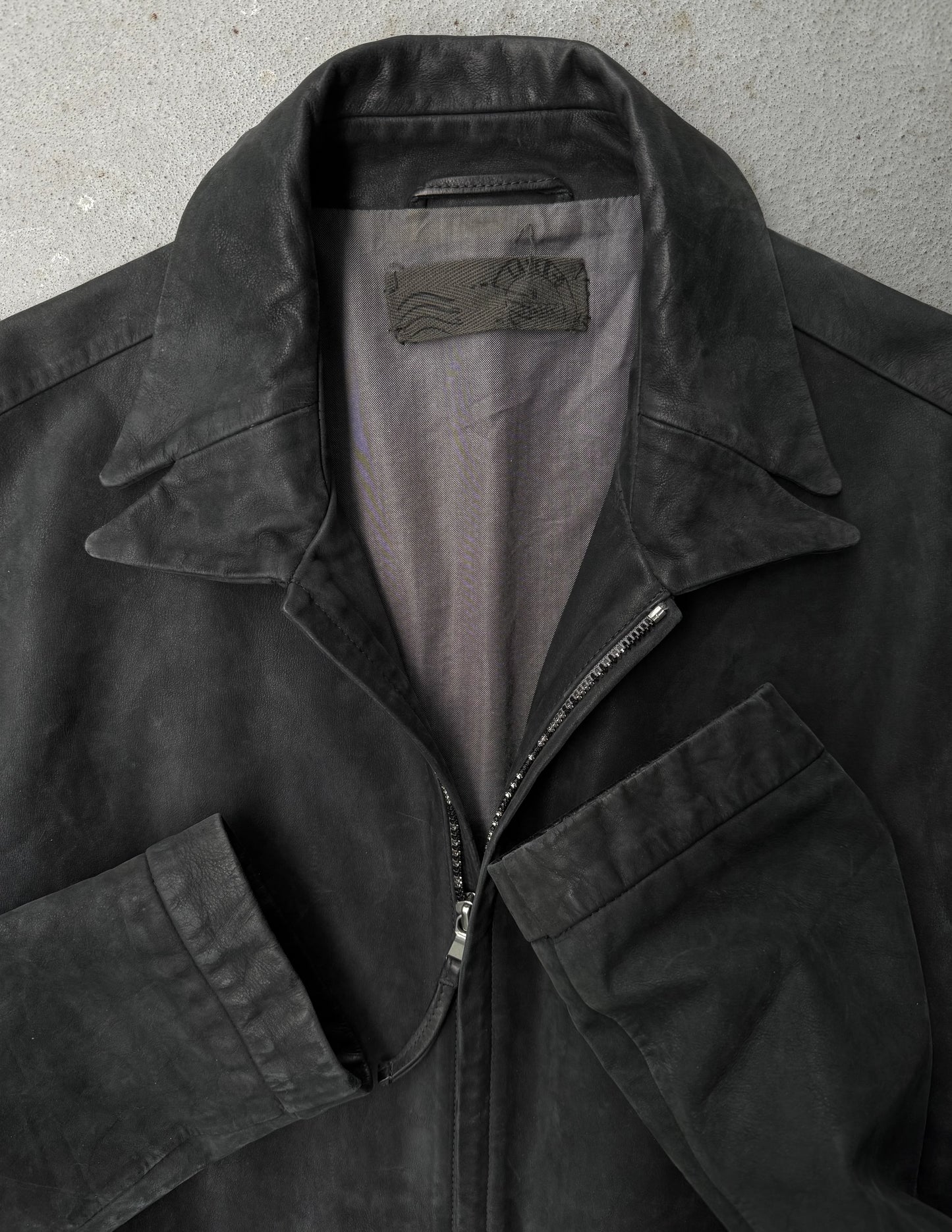 Black jacket with a visible brand label on a gray background