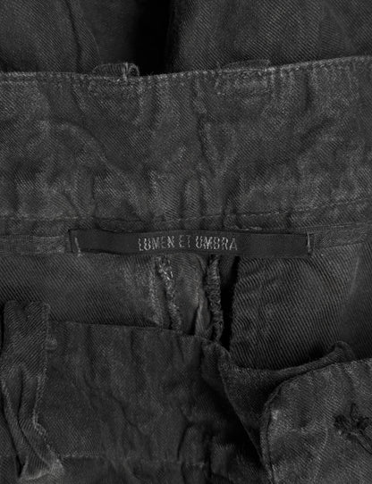 Close-up of a black denim jacket with 'Lumen et Umbra' branding on a dark background