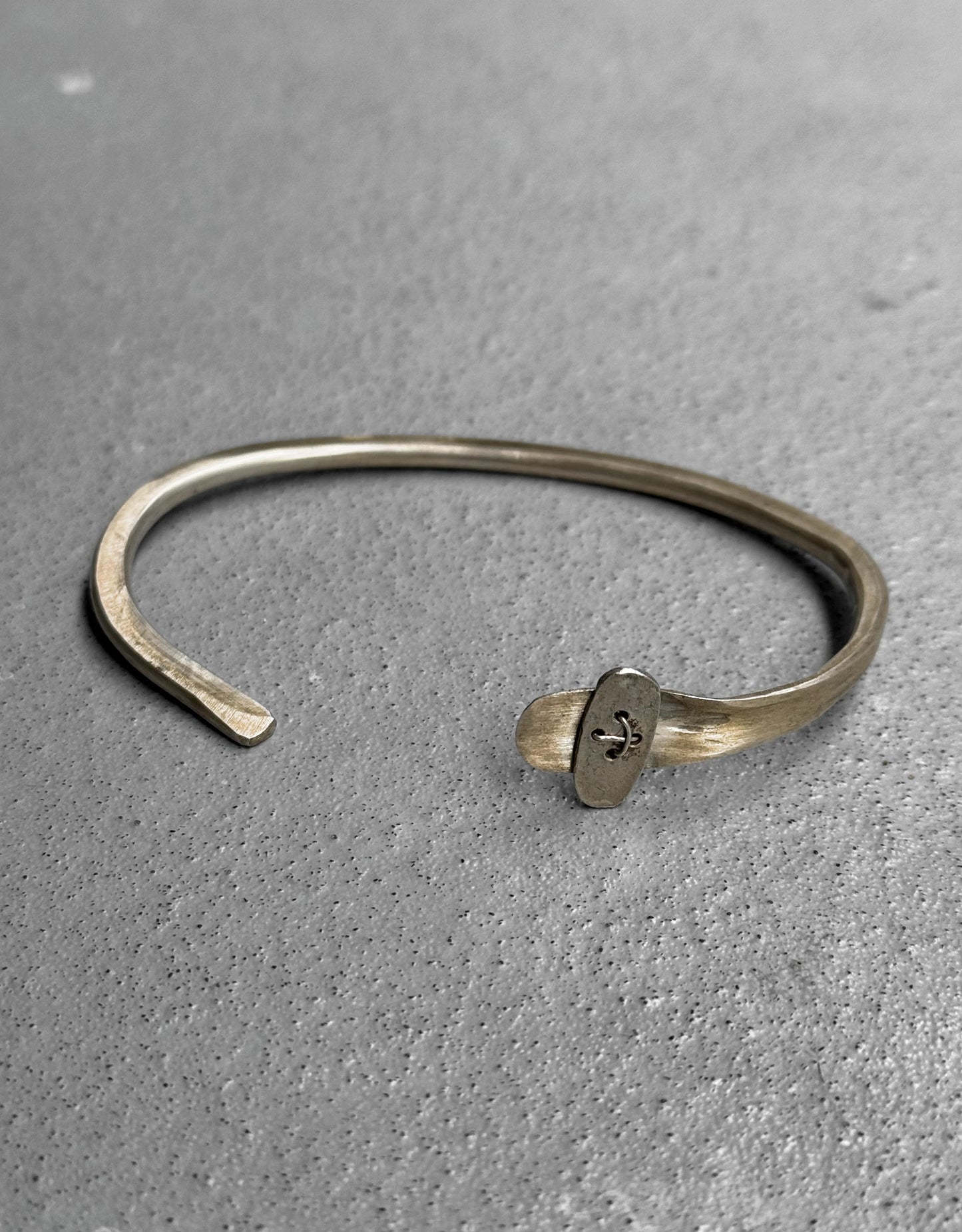 Silver bracelet with a clasp on a gray surface