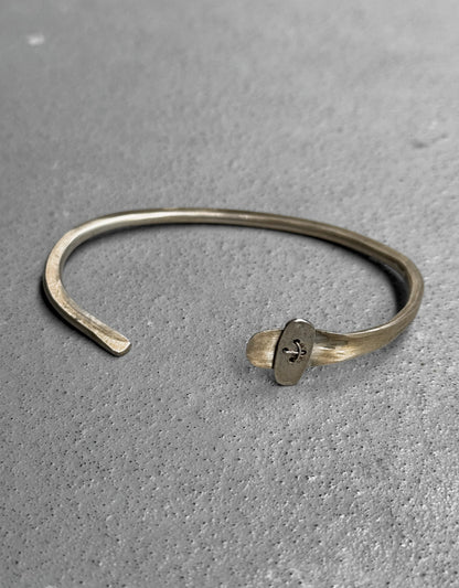 Silver bracelet with a clasp on a gray surface