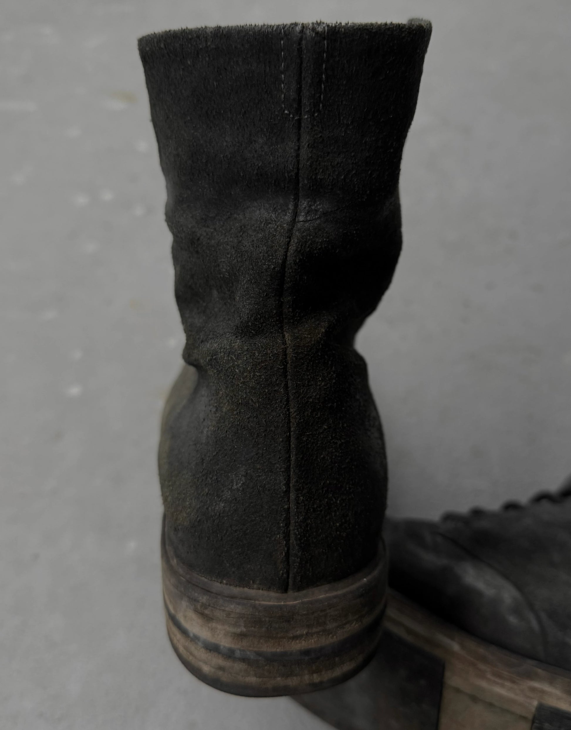 Dark brown leather boot on a gray surface