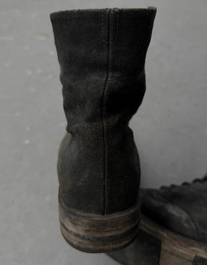 Dark brown leather boot on a gray surface