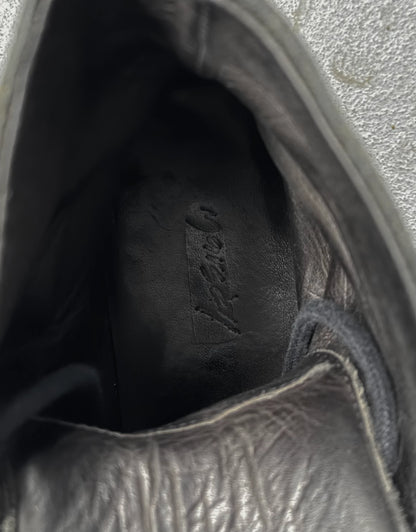 Close-up of a black leather shoe with visible stitching and brand logo.